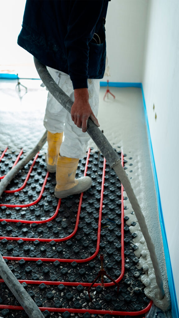 Operaio edile impegnato nella posa di massetto autolivellante su sistema radiante a pavimento