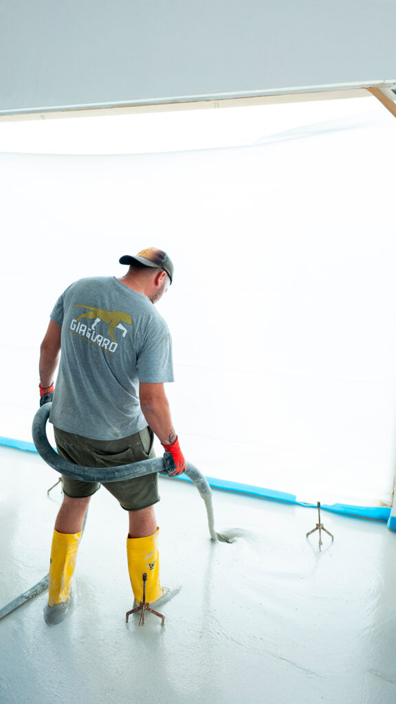 Operaio edile impegnato nella posa e pompaggio di massetto autolivellante