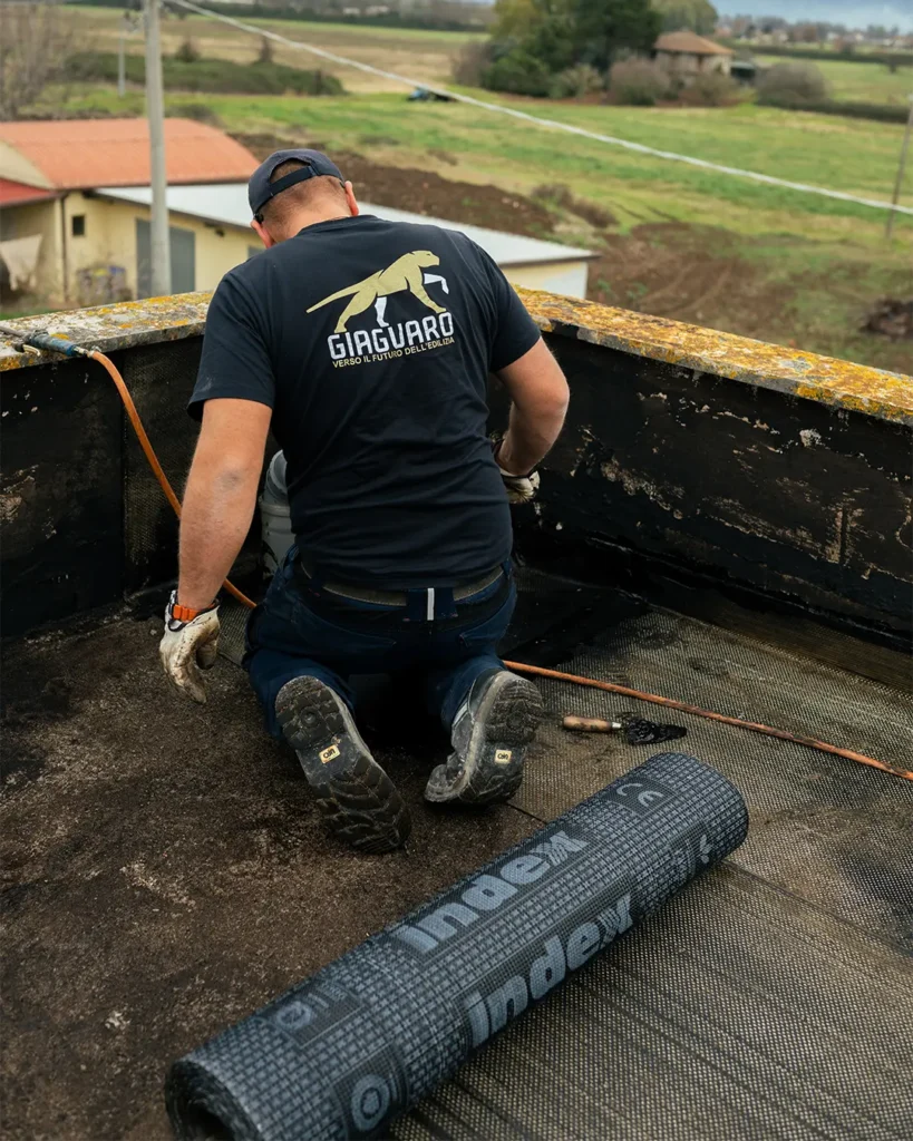 Operaio edile impegnato nella posa di guaina impermabilizzante
