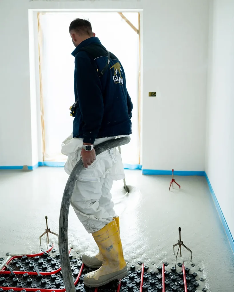 Operaio edile durante la posa di massetto autolivellante Fluocas su impianto radiante