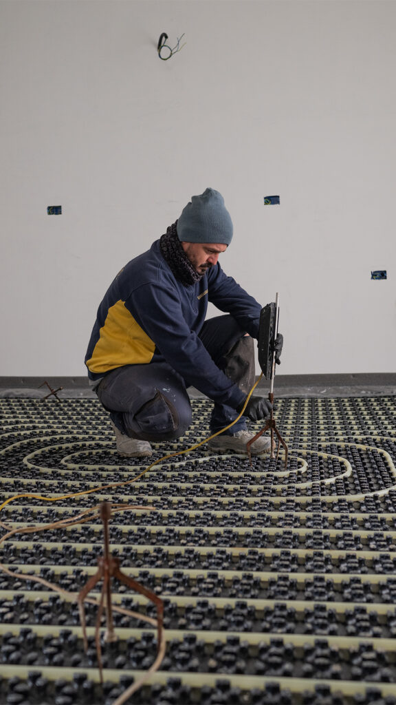 Operaio edile impegnato nella preparazione del cantiere per la posa di massetto per impianto radiante